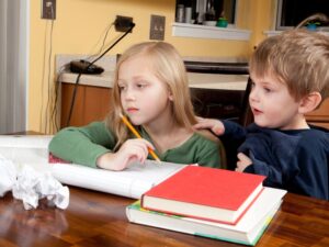 A young girl and boy study at home, illustrating challenges in maintaining a speech therapy practice at home.