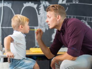 Speech therapist helping child with articulation disorders using visual prompts during speech therapy session.