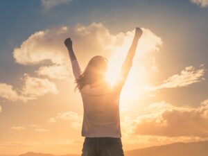 A woman raising her hands in triumph, symbolising success in overcoming fear through psychological strategies for personal growth.