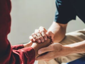 Therapist holding a client's hands, offering support and comfort. NDIS therapy.