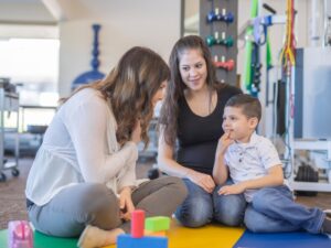 Speech therapist working with a child and mother in a therapy session focused on speech delay autism intervention.